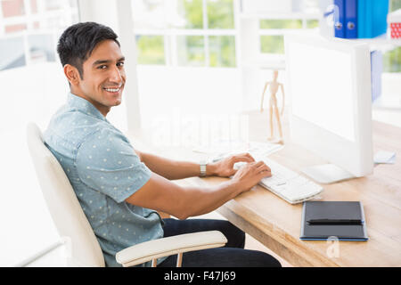 Portrait of smiling casual businessman working with computer and looking at camera Stock Photo