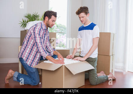 Smiling gay couple unpacking cardboard Stock Photo - Alamy