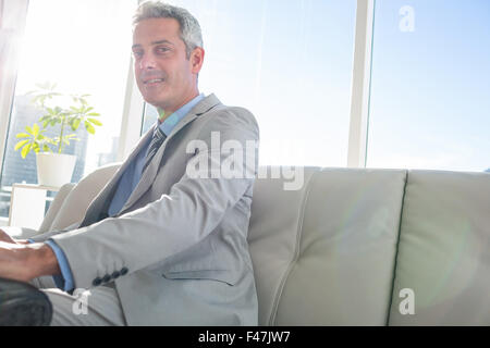 Happy business man sitting on sofa and looking at camera Stock Photo