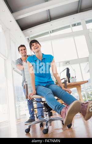Smiling photo editors having fun with on a swivel chair Stock Photo