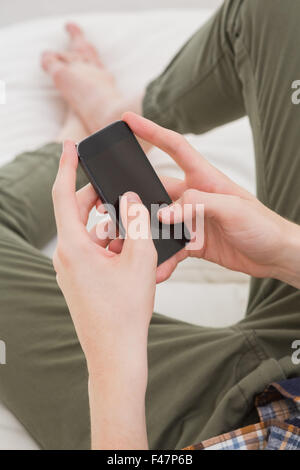 Man using his smartphone on sofa Stock Photo