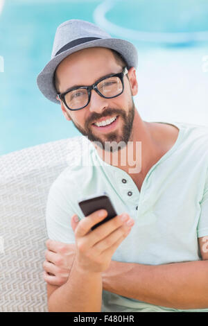 Happy handsome man looking at camera and holding smartphone Stock Photo