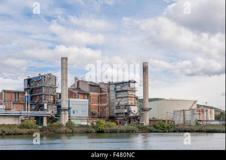 The old chemical factory with chimneys and silo on the banks of the river Stock Photo