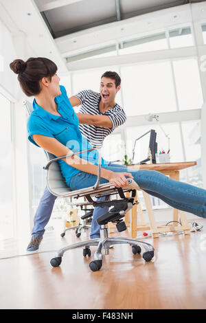 Smiling photo editors having fun with on a swivel chair Stock Photo