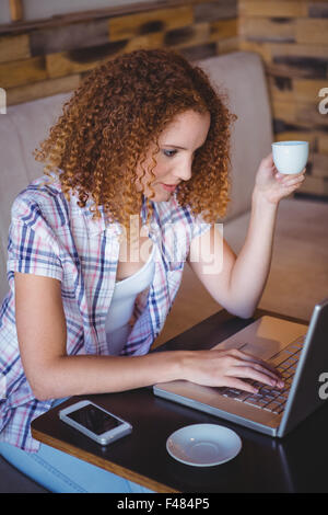 Happy smiling woman using her laptop and drinking coffee Stock Photo