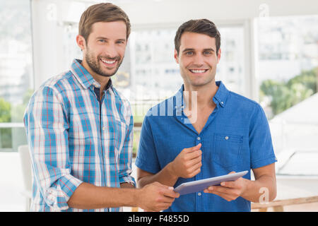 Creative businessmen smiling at camera and holding tablet Stock Photo