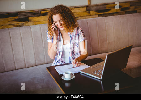 Happy smiling woman phoning and using her laptop Stock Photo