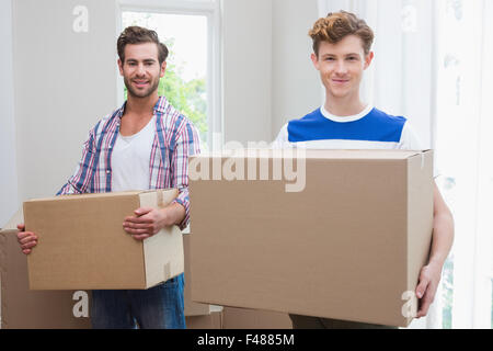 Happy homosexual couple holding box and looking at camera Stock Photo