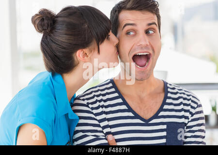 Surprised young designer getting a kiss from a co worker in creative
