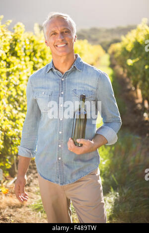 Smiling vintner holding bottle of wine Stock Photo