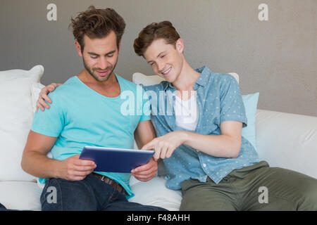 Cute homosexual couple using tablet on couch Stock Photo