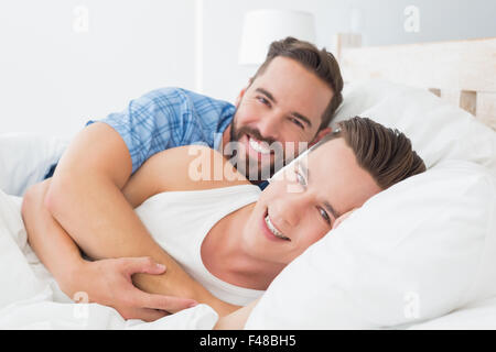 Happy homosexual couple hugging on bed Stock Photo