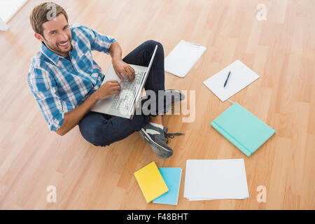 Creative businessman smiling at camera and typing on laptop Stock Photo