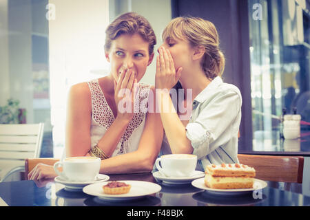 Beautiful women sitting and whispering secrets Stock Photo