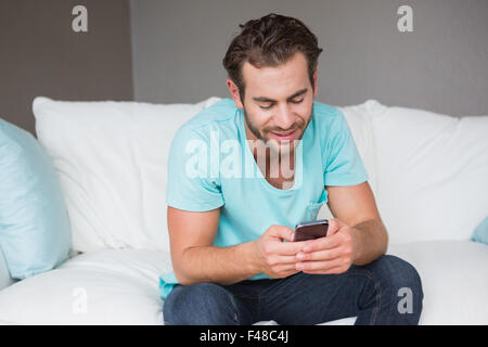 Handsome man using his smartphone on couch Stock Photo