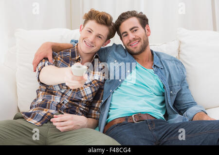 Happy homosexual couple hugging and using remote control Stock Photo