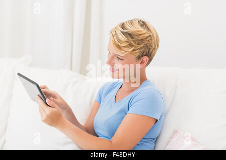 Smiling woman sitting on couch and using tablet computer Stock Photo