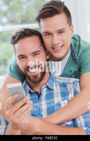 Smiling homosexual couple men looking at smartphone Stock Photo
