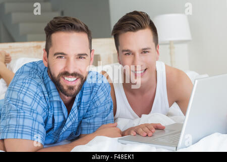 homosexual couple looking at camera and using laptop Stock Photo