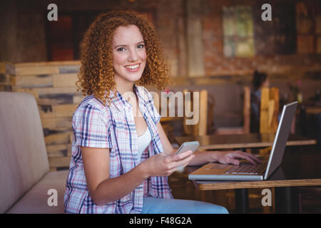 Portrait happy smiling woman using her smartphone and laptop Stock Photo