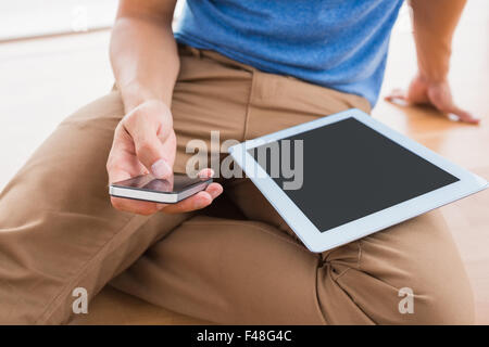 Businessman sitting on the floor using tablet Stock Photo