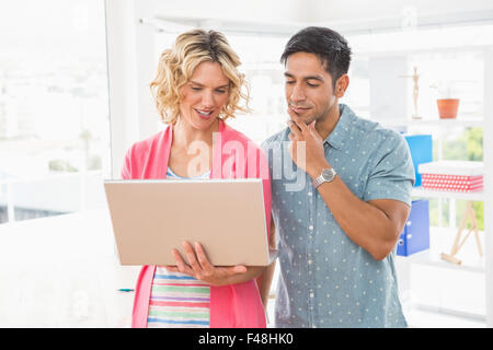 Colleagues standing and using laptop together Stock Photo