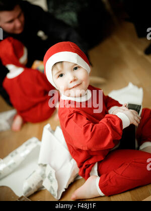 Boy dressed as Santa Claus opening Christmas presents, Sweden. Stock Photo