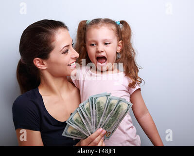 Happy smiling family holding dollars and thinking how to spend the money. Portrait on blue background with empty copy space Stock Photo