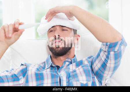 Ill man checking temperature on thermometer Stock Photo