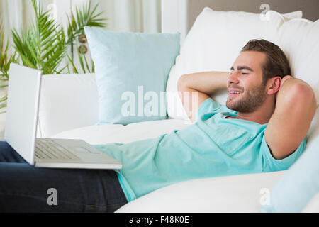Relaxed handsome man using laptop on couch Stock Photo