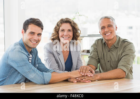 Creative business people looking at camera and joining hands Stock Photo