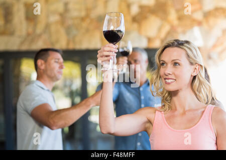 Smiling woman with wineglass in front of group doing wine tasting Stock Photo