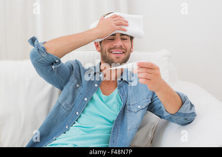 Sick handsome man sitting on sofa Stock Photo