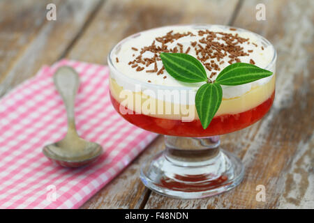Traditional English strawberry trifle in transparent dessert glass on rustic wooden surface Stock Photo
