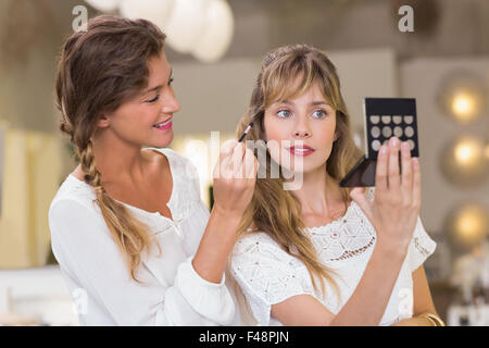 Employee applying makeup on costumer Stock Photo