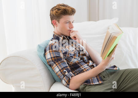 Handsome man reading book on couch Stock Photo