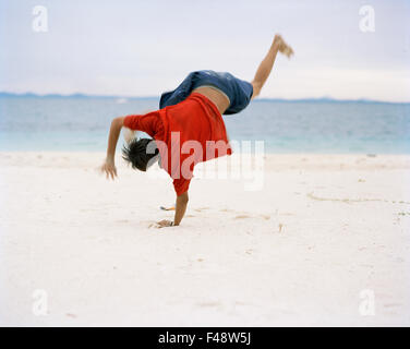 A teenager doing a vault at the beach Stock Photo