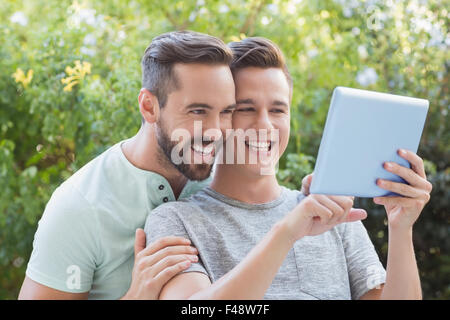 Happy homosexual couple using tablet computer Stock Photo