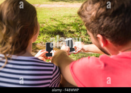 Couple using their mobile phone in the park Stock Photo