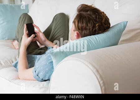 Rear view of young man using his smartphone on couch Stock Photo
