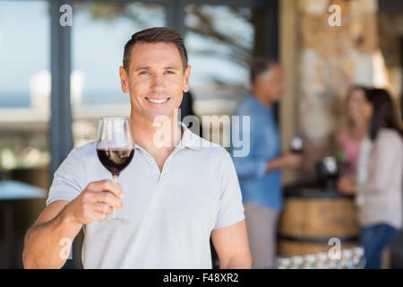 Smiling man with wineglass in front of group talking and drinking wine Stock Photo