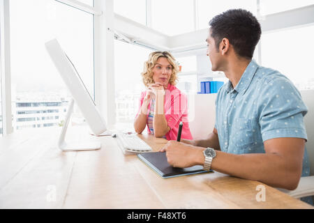 Colleagues speaking together at desk Stock Photo