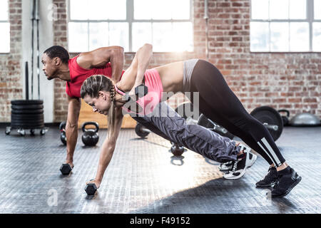 Fit couple doing push ups with dumbbells Stock Photo