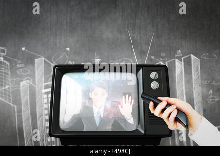 Composite image of hand using remote control Stock Photo