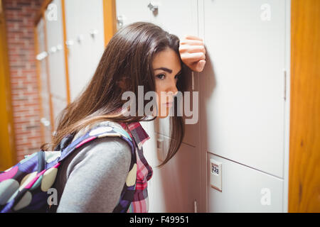 Thoughtful student leaning on locker Stock Photo