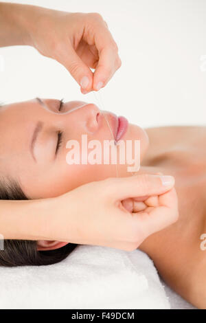 Hands threading beautiful womans face Stock Photo