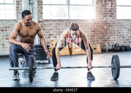 Trainer helping woman with lifting barbell Stock Photo