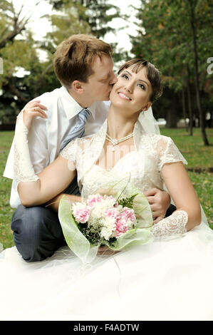 Vertical newly married couple of bride in wedding dress kissing head of