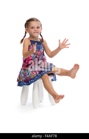 Little girl in a colored dress on a chair Stock Photo