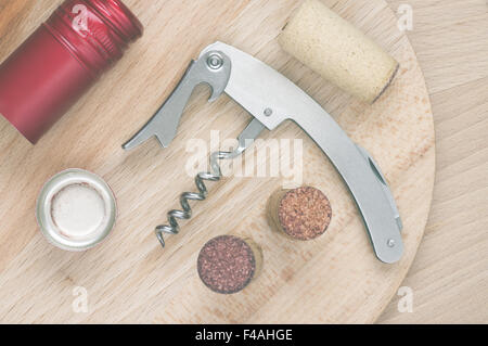 Corkscrew, wine corks and cap on a wooden table top view Stock Photo